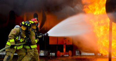 Firefighters extinguishing a fire in a factory with a fire hose